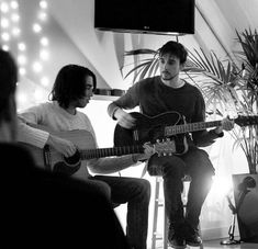 two people sitting in chairs playing guitars