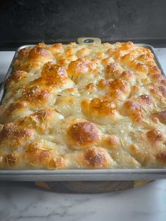 a casserole dish sitting on top of a stove with cheese and bread toppings