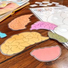 several pieces of cut out paper sitting on top of a wooden table next to magazines