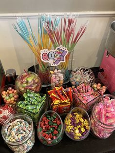 a table topped with lots of candy and candies next to a cup filled with lollipops