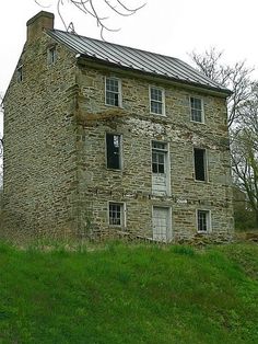 an old stone house sitting on top of a lush green hillside