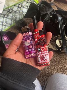 someone is holding two small lighters in their hand, one has hello kitty and the other has snowflakes on it