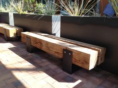 two wooden benches sitting next to each other on a brick floor in front of a planter