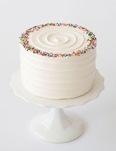 a white cake topped with sprinkles on top of a white cake plate