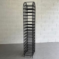 a black metal rack stands against a white brick wall