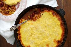 a skillet filled with baked beans and cheese next to a bowl full of other food