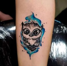 an owl tattoo on the arm with blue watercolors and stars in the background