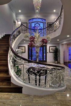 an elegant staircase in a house with stained glass windows and chandelier above it