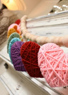 yarn hearts are hanging from a wooden frame