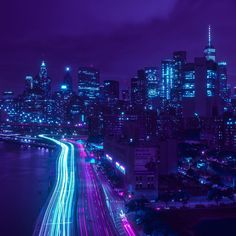 the city skyline is lit up at night with bright lights and streaks of light in the foreground