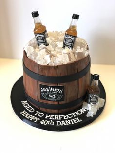 a birthday cake made to look like a barrel with three bottles of whiskey in it