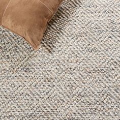 a brown pillow sitting on top of a gray carpet