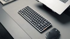 a computer keyboard sitting on top of a desk next to a mouse and laptop monitor