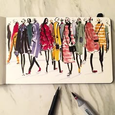 a drawing of a group of women's coats on a piece of paper next to markers