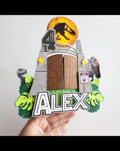 someone is holding up a paper cut out of a house with the word alex on it