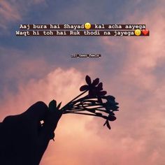 a person holding a flower in their hand with the sky and clouds behind them as the sun sets