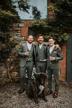 three men in suits posing with a dog