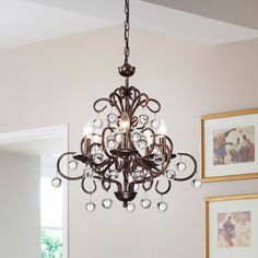 a chandelier hanging from a ceiling in a room with pictures on the wall