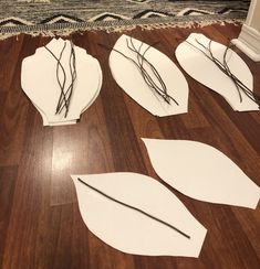 four pieces of paper cut out to look like leaves on the floor next to a rug