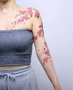 a woman with flowers painted on her arm and shoulder is posing for the camera while wearing a gray top