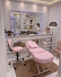 a pink chair sitting in front of a mirror on top of a counter next to a stool