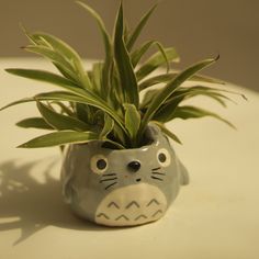 a small ceramic animal planter with green plants in it