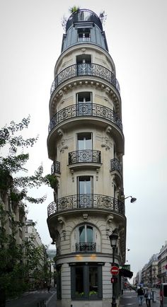 a tall building with balconies on the top of it's sides next to a street