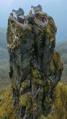 people are standing on the edge of a cliff with two towers in the middle of it