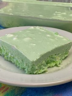 a white plate topped with a piece of cake on top of a blue and green table cloth