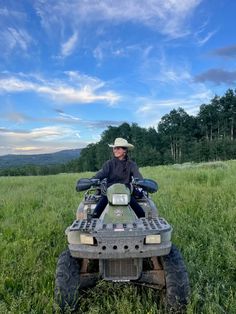 a man riding on the back of an atv in a grassy field under a blue sky