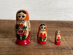 three nesting dolls sitting on top of a wooden table next to each other with flowers painted on them