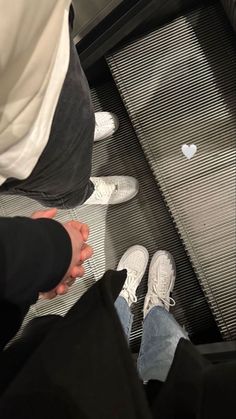 two people standing at the bottom of an escalator with their feet in the air