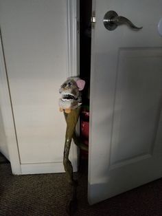 a stuffed animal is sticking its head out from behind a door handle in a room