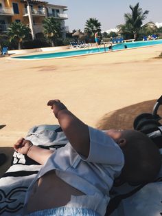 a baby laying on top of a towel next to a pool