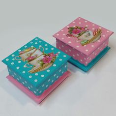 two colorful boxes with polka dots and teacups on the top one has pink flowers