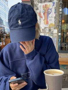 a woman sitting at a table with a cup of coffee and cell phone