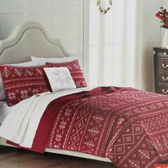 a bed with red and white comforters in a room