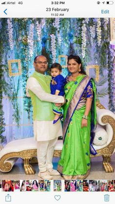 a man and woman holding a baby in front of a backdrop with flowers on it