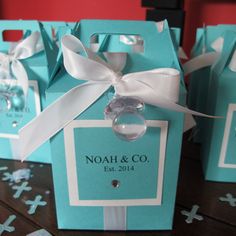 small blue boxes with white ribbon tied around the handles and tags on them, sitting on a table