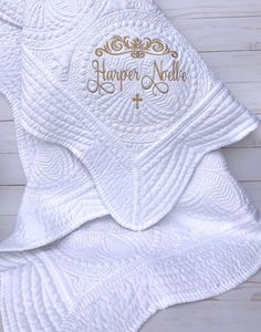 This is a very special embellished baby blanket with gold nursery decor in mind. The white quilt is made of 100% cotton and sized at 36 x 46 inches. It has 12 round quilted medallions and a beautiful scalloped edge. This will be the centerpiece of any baby nursery (besides the new baby of course!) and will surely be a keepsake. This custom baby blanket features a gold flourish and is personalized with names. It can be made with the cross making it a perfect religious baby gift or without dependi Gold Nursery Decor, Personalized Baby Quilt, Embroidered Items, Gold Nursery, Baptism Ideas, Custom Baby Blanket, Embroidery Monogram, Baby Christening, Diaper Cakes