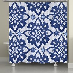 a blue and white shower curtain with an ornate design on it's side, next to a bathtub