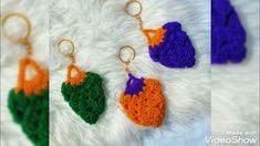 crocheted keychains with orange, green and purple hearts on them sitting on a white furnishing