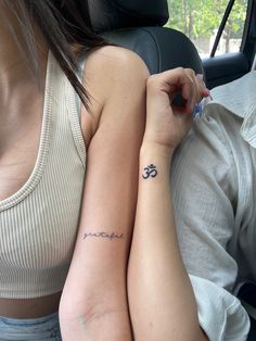 two women with tattoos on their arms sitting in a car