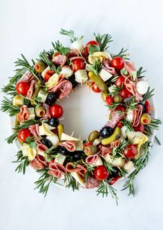 a wreath made out of different types of vegetables and meats on a white surface