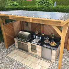 an outdoor kitchen with grill, sink and counter top in the middle of graveled area