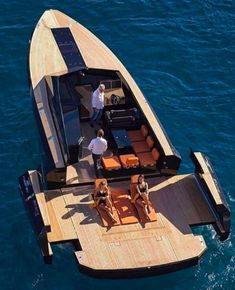 two people are sitting on the back of a boat in the water while another person stands near them