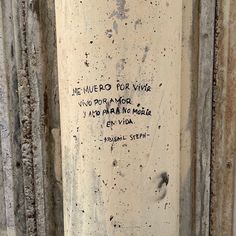 graffiti written on the side of a cement pillar in an old building with peeling paint