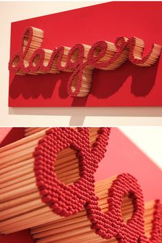 the word love spelled with matchesticks in front of a red wall