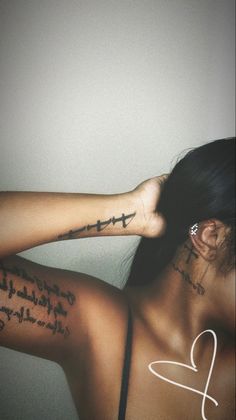 a woman with cross tattoos on her arm and shoulder, behind her is the word love written in cursive writing