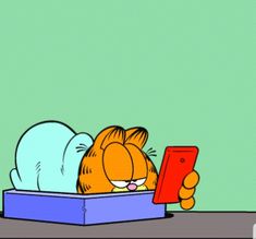 garfield the cat is laying in a box and looking at his cell phone while reading it